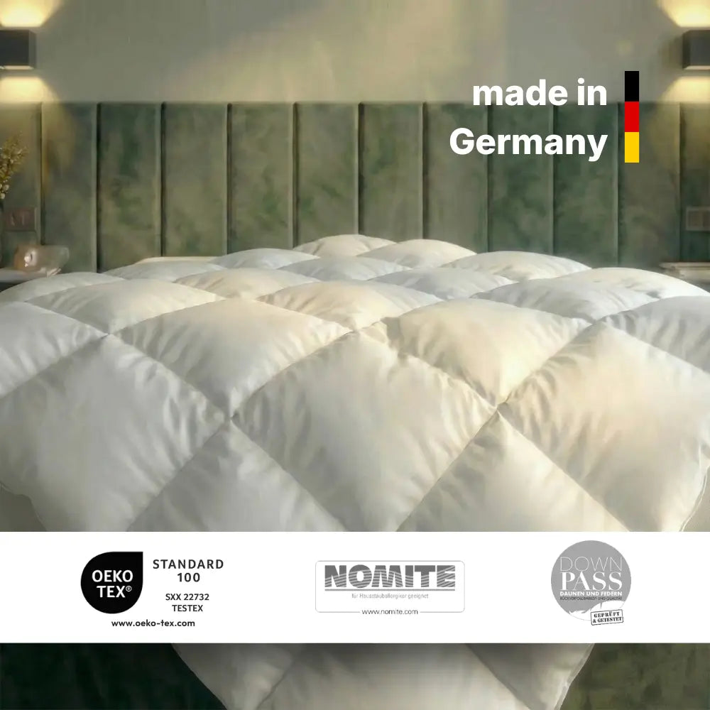 Weiße gesteppte Bettdecke auf modernem Bett mit grünem Kopfteil, gekennzeichnet mit ‚Made in Germany‘ sowie OEKO-TEX Standard 100, NOMITE und Downpass Zertifizierungen