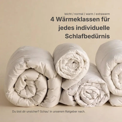 Mehrere gerollte Premium Daunen- und Federdecken nebeneinander, Darstellung von vier Wärmeklassen für individuelles Schlafbedürfnis von leicht bis extrawarm