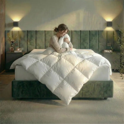 Frau sitzt entspannt im Bett und kuschelt sich in eine Premium Daunen- und Federdecke, voluminöse Steppung sorgt für wohlige Wärme und hohen Schlafkomfort