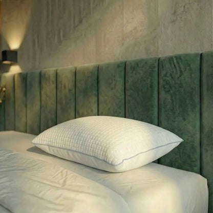Weißes Essential Kühlkissen mit strukturierter Oberfläche liegt flach auf einem Bett vor grünem Kopfteil
