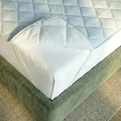 Aufgeschlagene Ecke der TopCool Matratzenauflage zeigt weiche Polsterung und kühlende, atmungsaktive Materialschichten für ein angenehmes Schlafklima